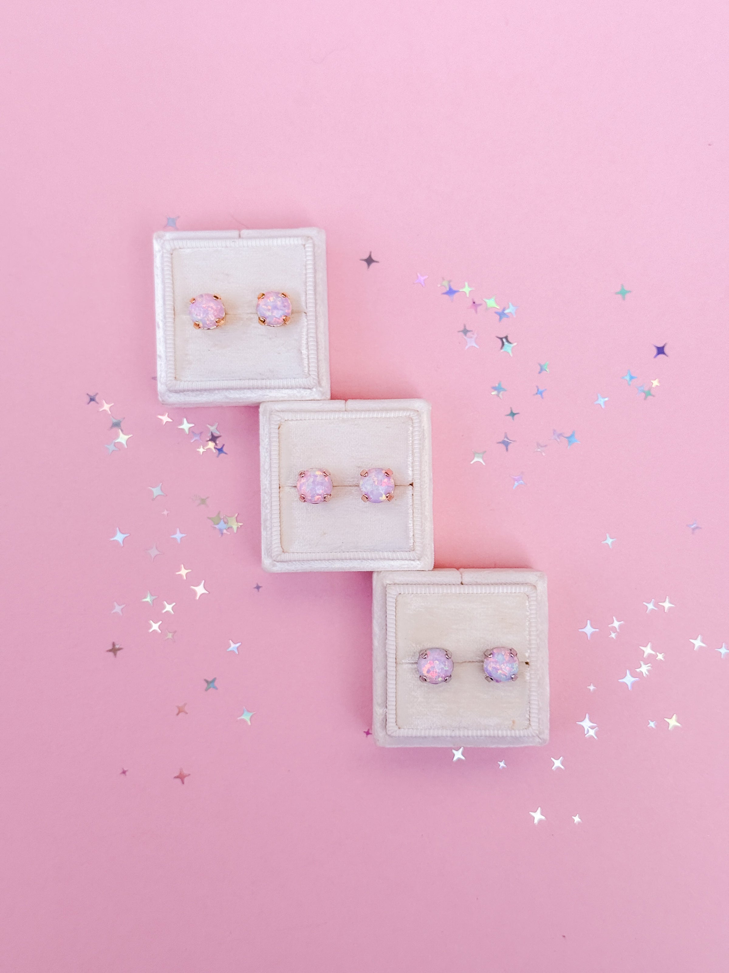 3 pairs of pink opal stud earrings on a pink background.