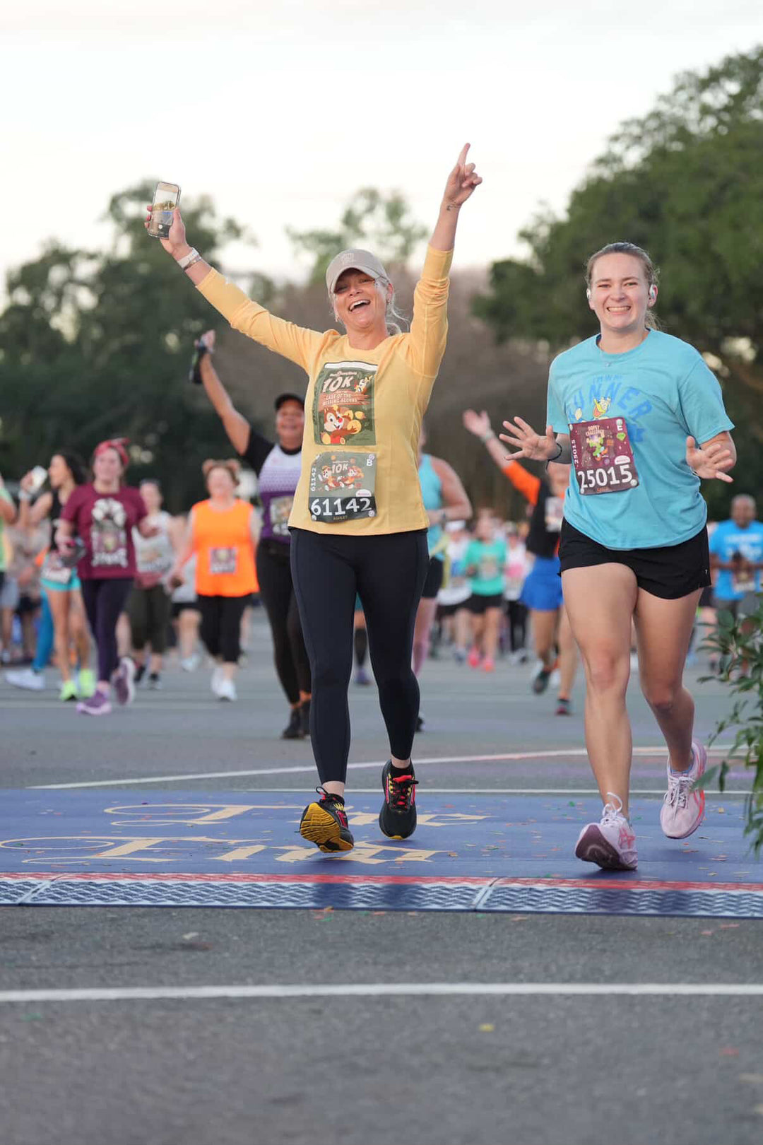 Two women running on a track with one celebrating a finish
