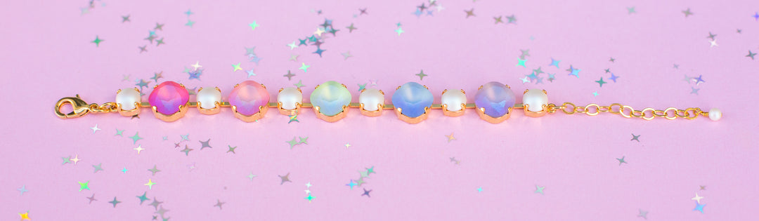 Gold bracelet with colorful beads on a pink background