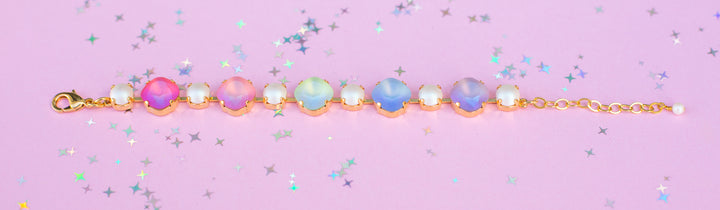 Gold bracelet with colorful beads on a pink background