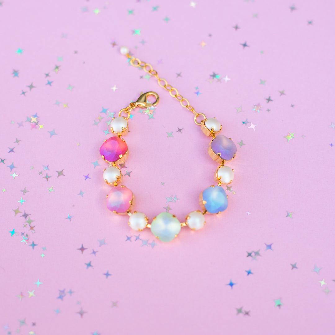 Colorful beaded bracelet on a pink background with star-shaped confetti