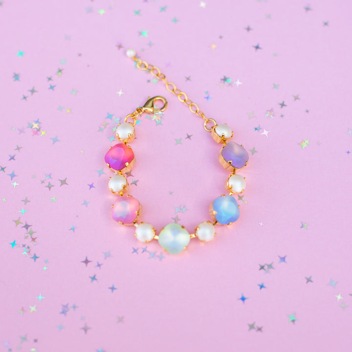 Colorful beaded bracelet on a pink background with star-shaped confetti
