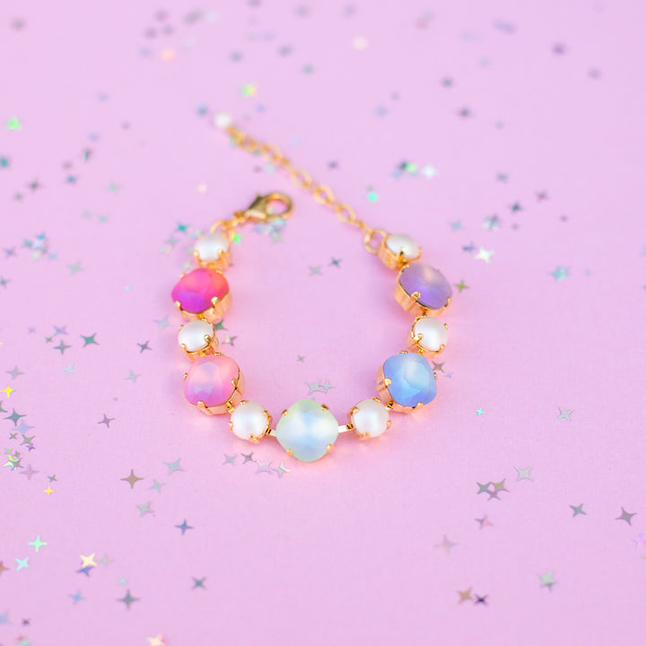Multicolored beaded bracelet on a pink background with star-shaped glitter