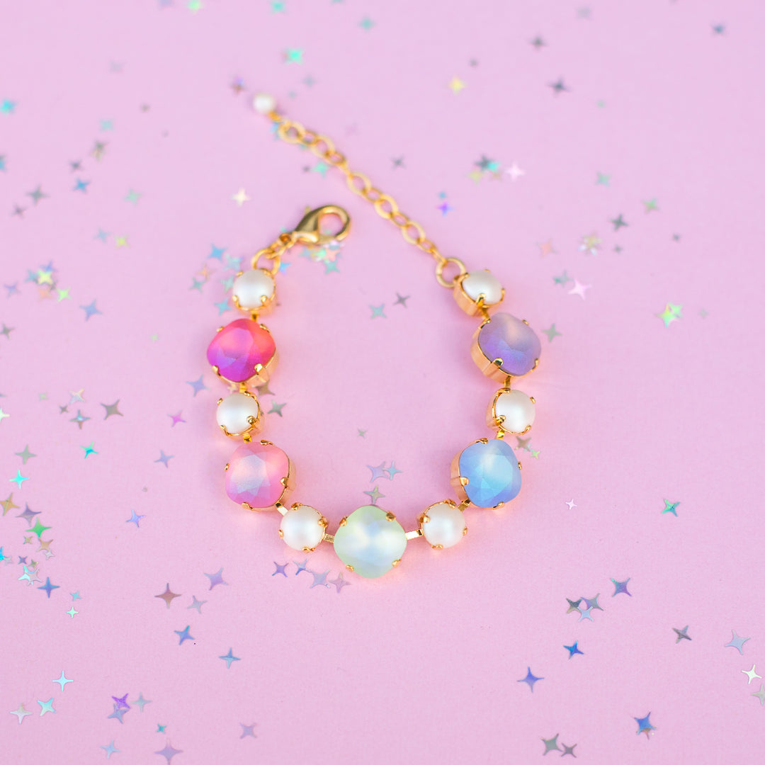 Multicolored beaded bracelet on a pink background with star-shaped confetti