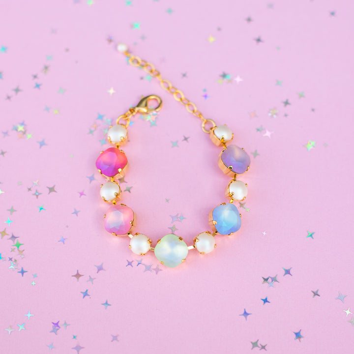 Multicolored beaded bracelet on a pink background with star-shaped confetti