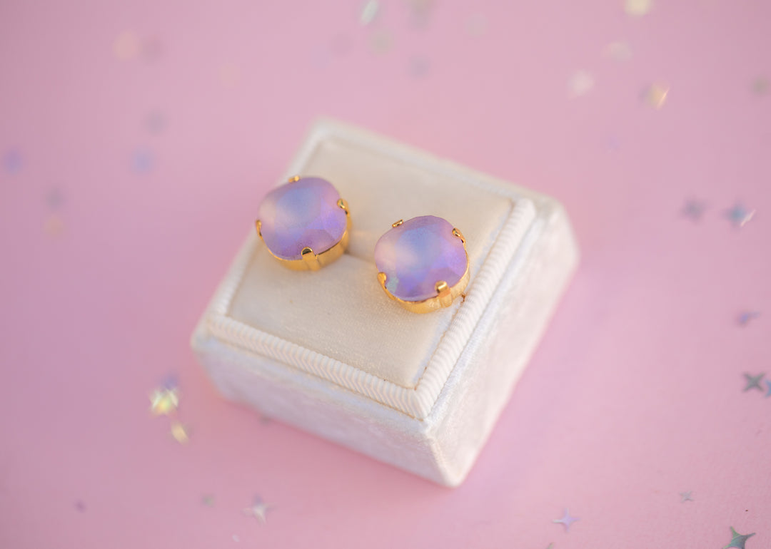 Heart-shaped opal earrings in gold setting on a pink background