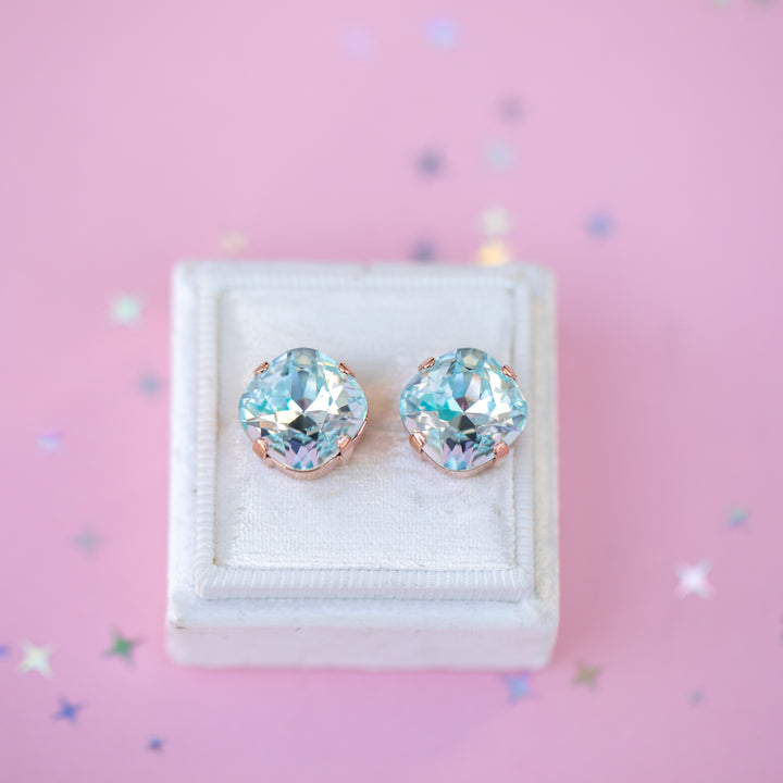 Pair of earrings with gemstones in a white box on a pink background