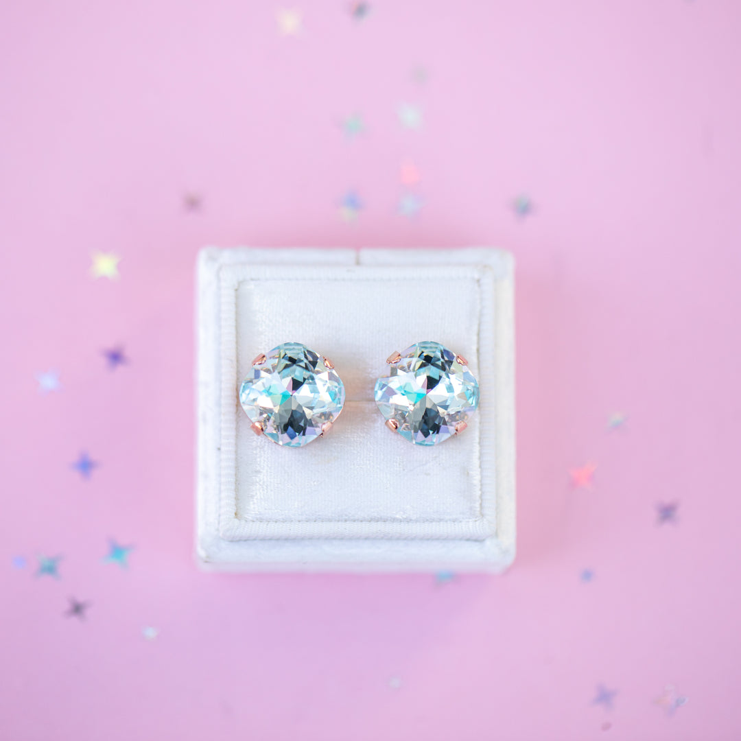 Pair of crystal stud earrings in a white box on a pink background