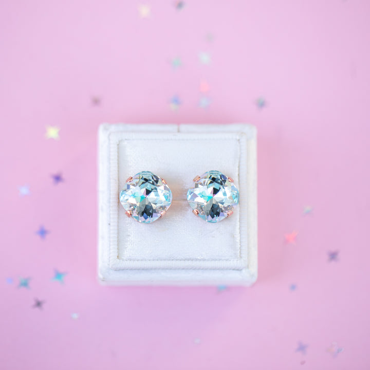 Pair of crystal stud earrings in a white box on a pink background