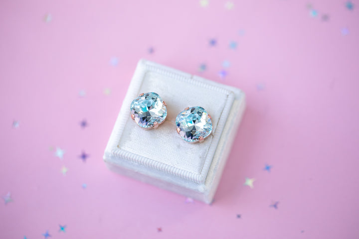 Pair of crystal stud earrings on a white box with a pink background