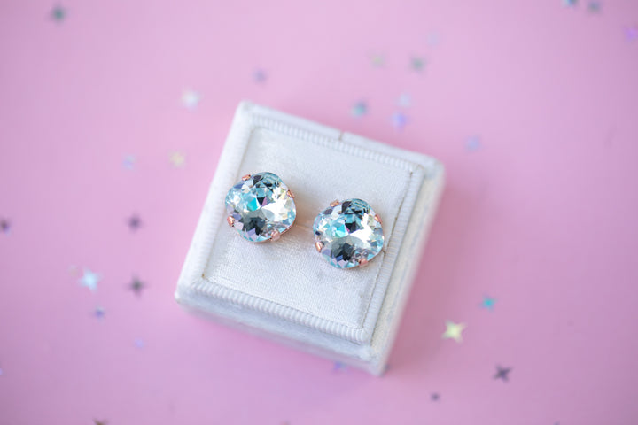 Pair of crystal earrings against a pink background with star-shaped confetti.