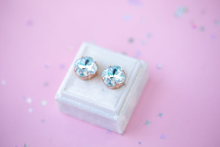 Pair of crystal stud earrings on a white box with a pink background