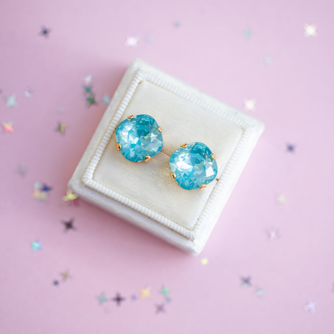 Turquoise earrings on a white cushion with a pink background
