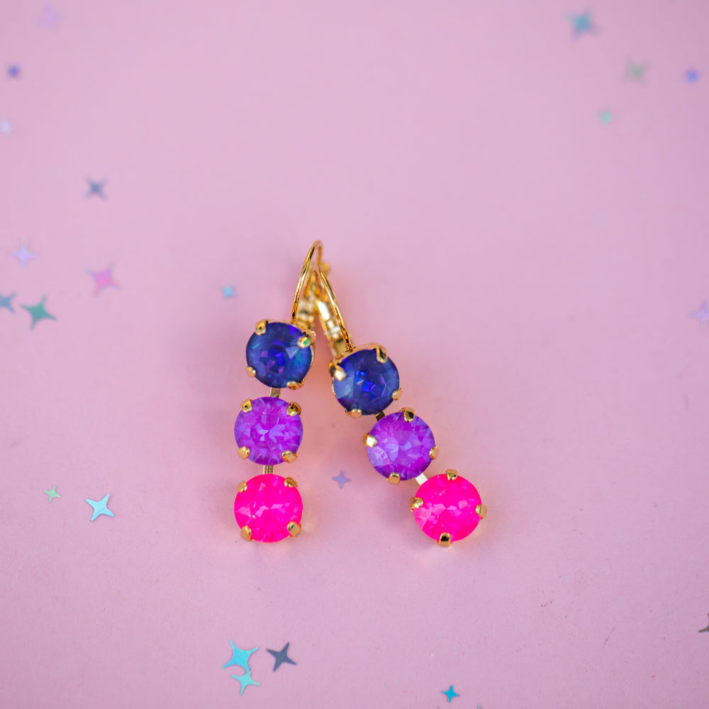 Colorful gemstone earrings on a pink background with star decorations