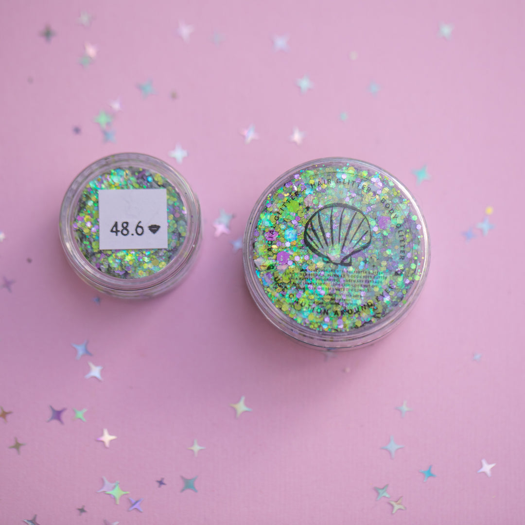 Two containers of glitter with a shell design on a pink background with star confetti.