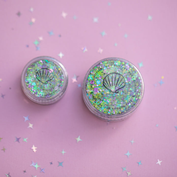 Two small round containers with glittery lids on a pink background with star-shaped confetti.