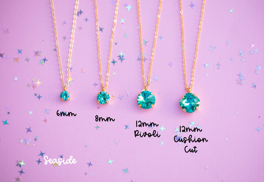 Four gold necklaces with green gemstones on a purple background with star patterns.