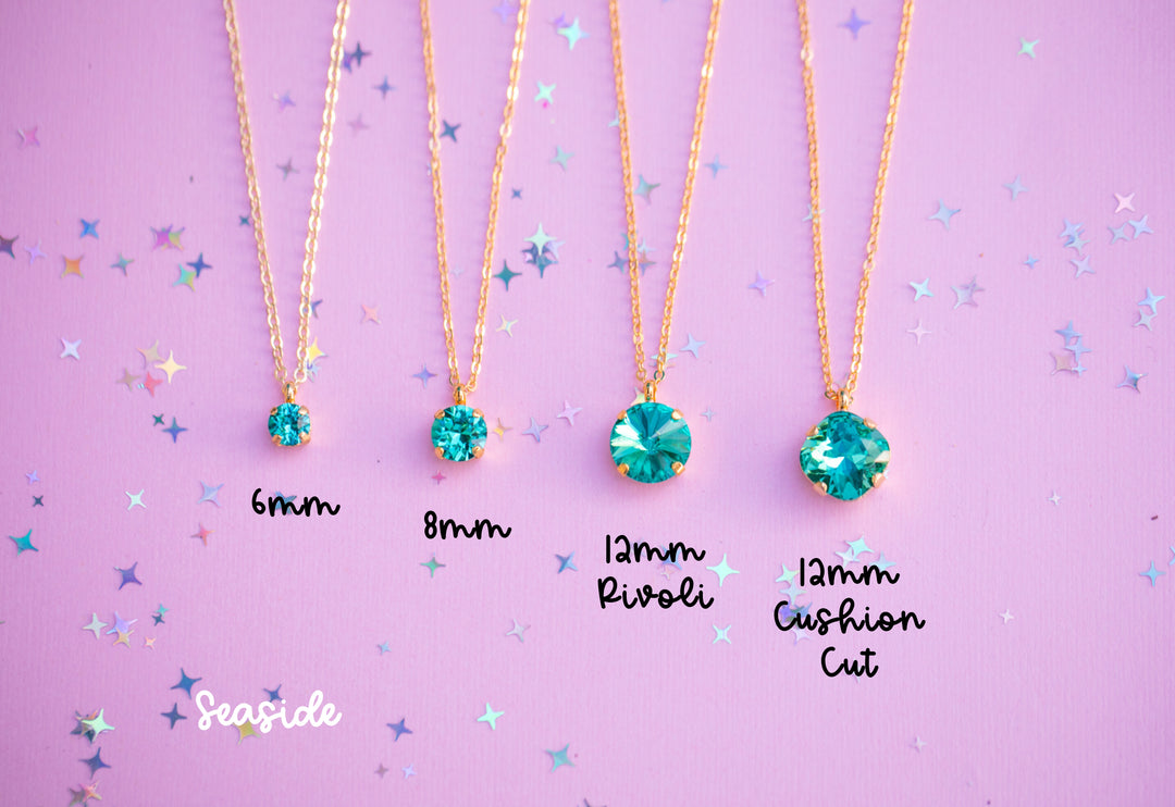 Four gold necklaces with green gemstones on a purple background with star patterns.
