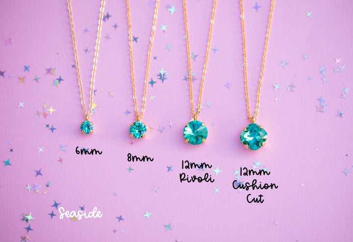 Four gold necklaces with green gemstones on a purple background with star patterns.