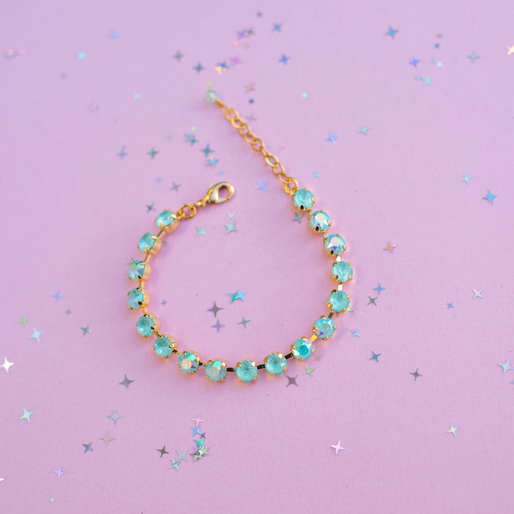 Gold bracelet with turquoise beads on a purple background