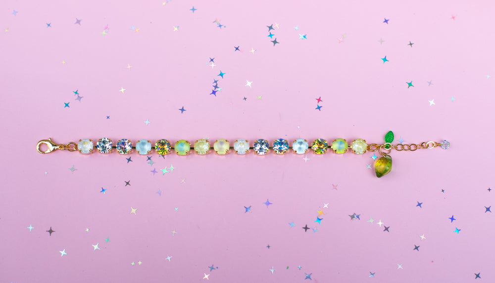 Multicolored gemstone bracelet on a pink background with star-shaped confetti