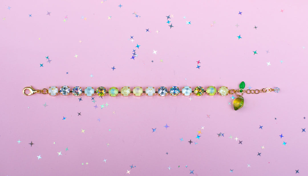 Multicolored gemstone bracelet on a pink background with star-shaped confetti