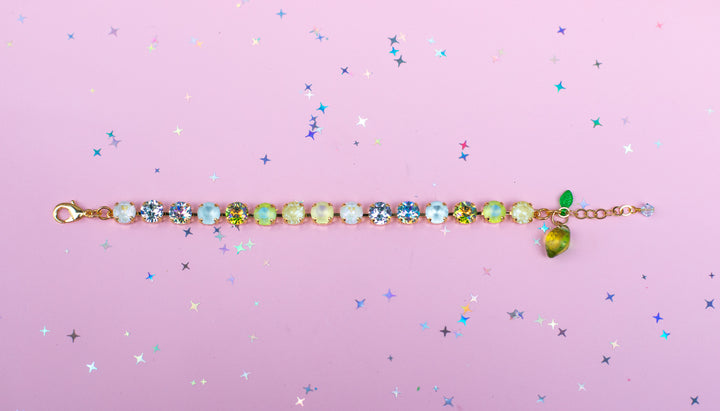 Multicolored gemstone bracelet on a pink background with star-shaped confetti