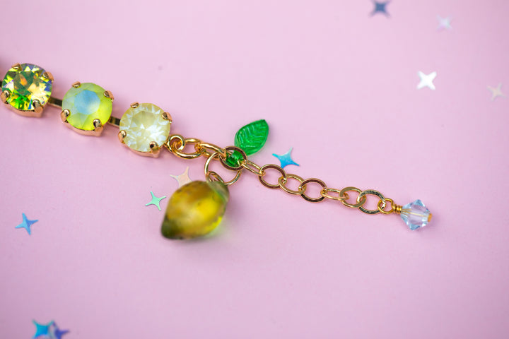 Bracelet with green gemstones and leaf charm on a pink background