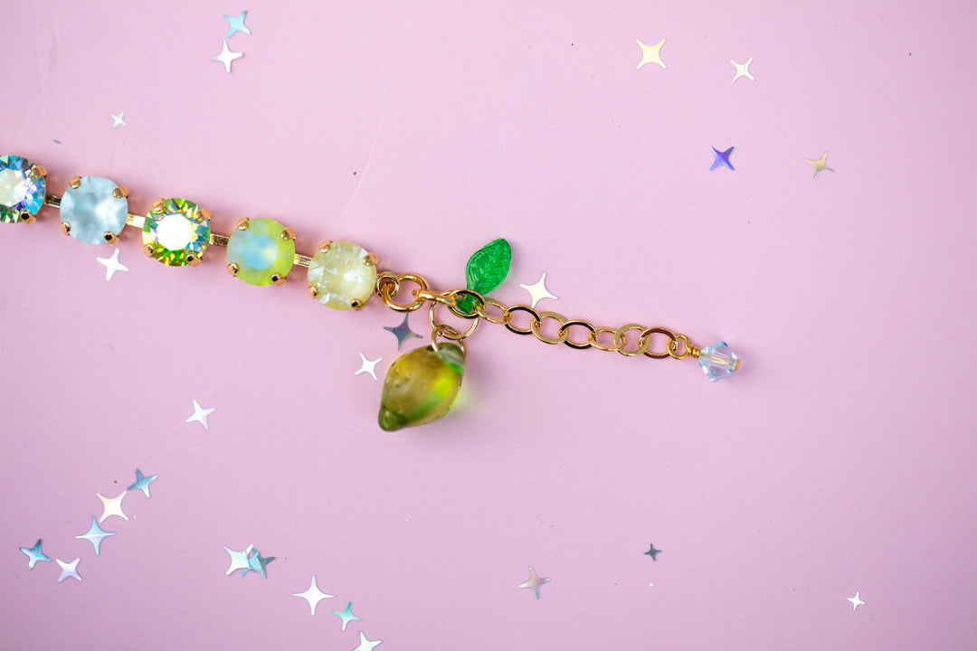 Bracelet with green gemstones and gold chain on a pink background
