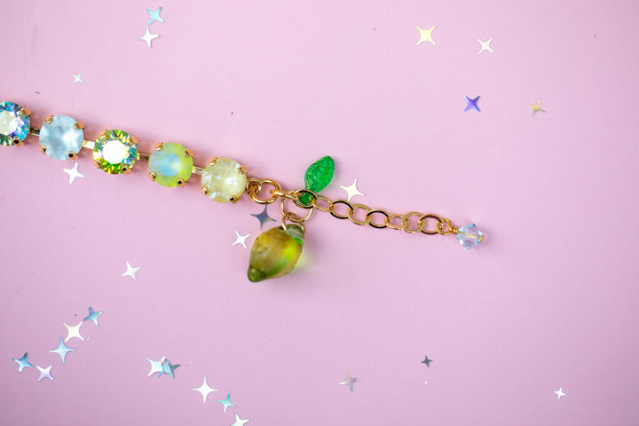 Bracelet with green gemstones and gold chain on a pink background