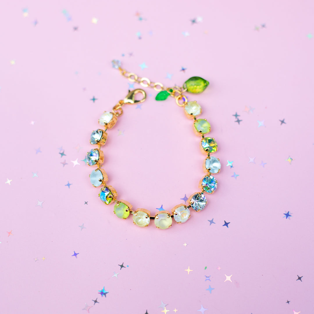 Gold bracelet with colorful beads on a pink background with star-shaped confetti