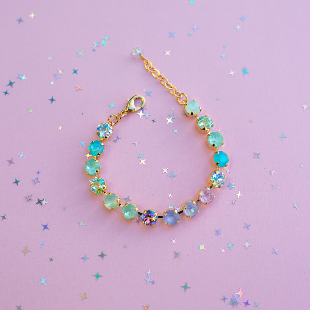 Gold bracelet with colorful beads on a purple background with star-shaped confetti