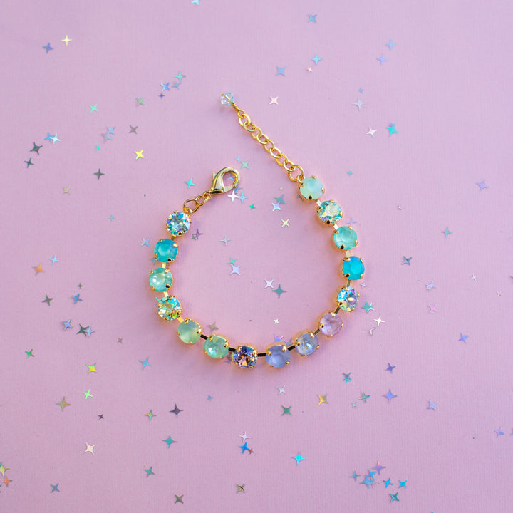 Bracelet with colorful beads on a pink background with star-shaped confetti