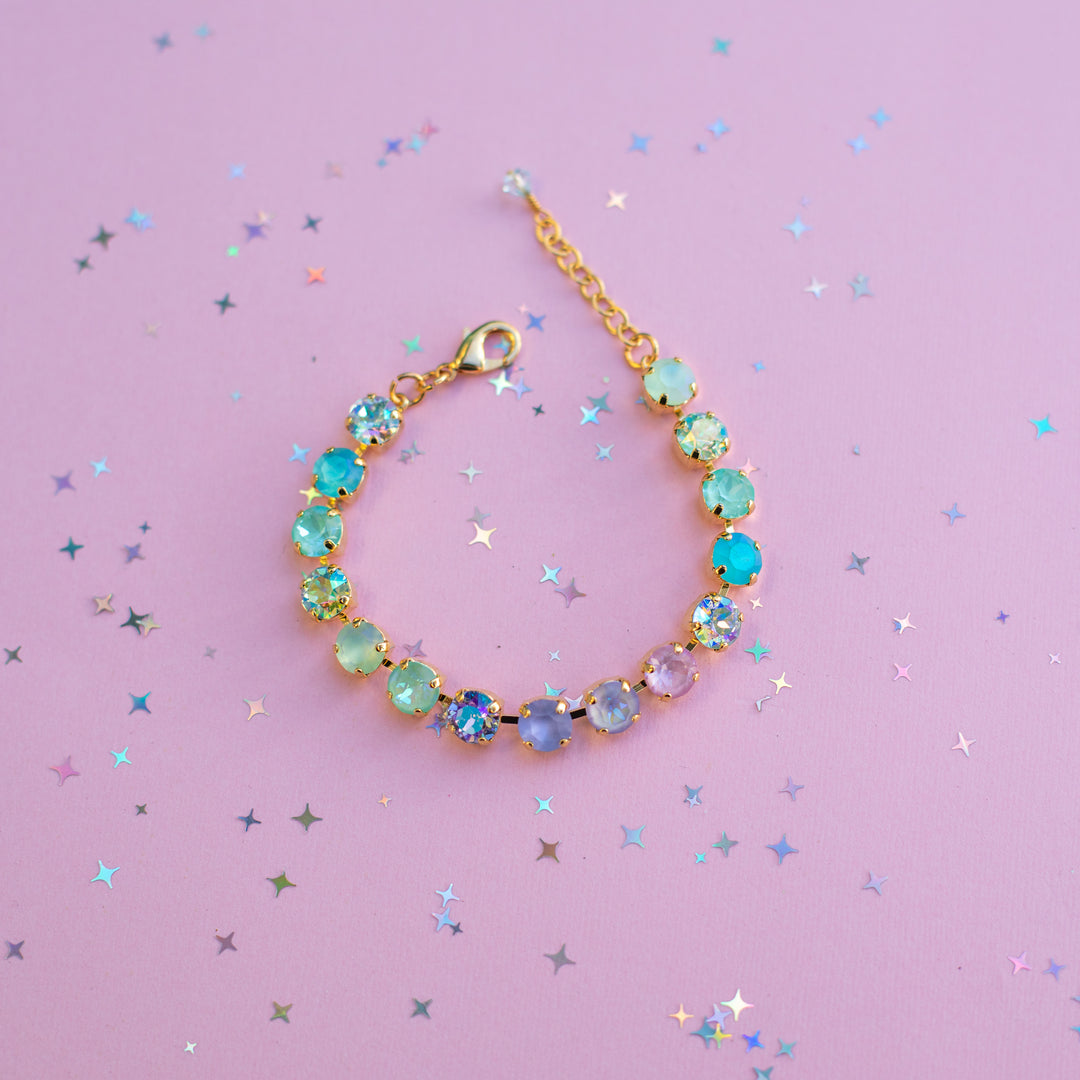 Multicolored crystal bracelet on a pink background with star-shaped confetti