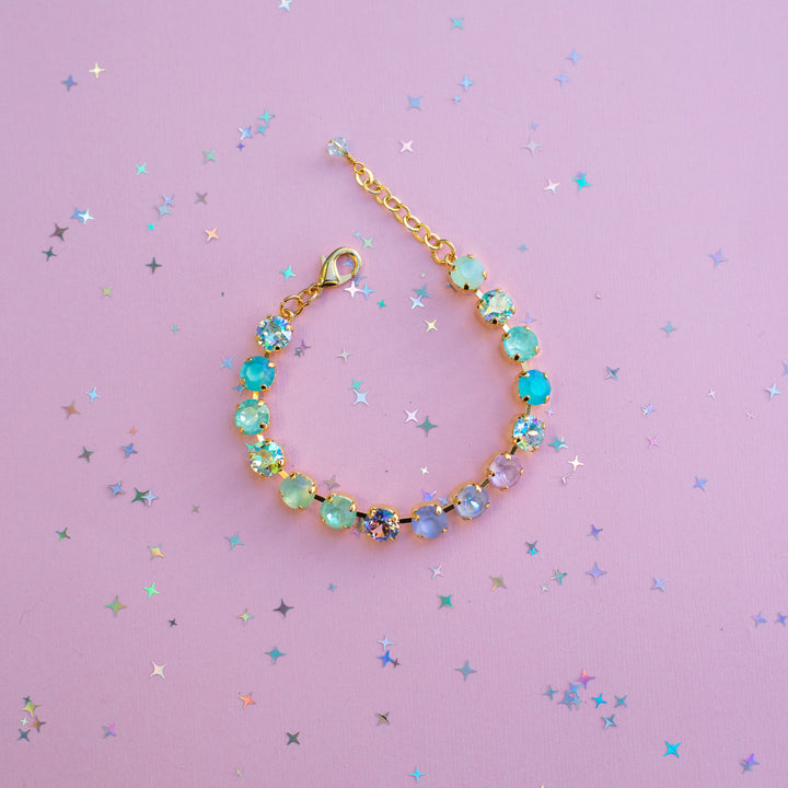 Bracelet with colorful beads on a pink background with star-shaped confetti