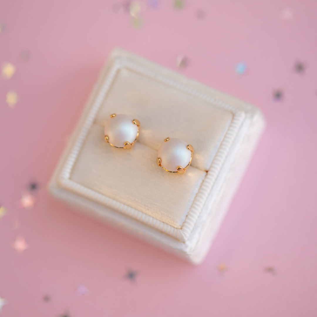 Pearl earrings with gold accents on a pink background