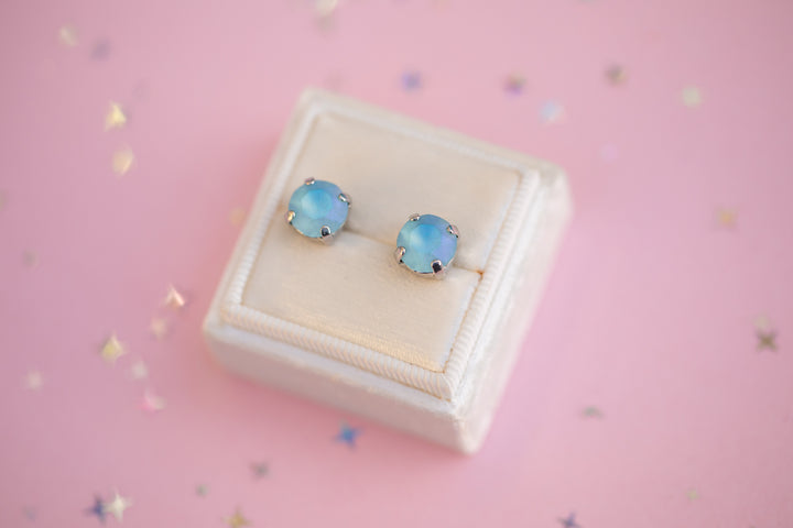 Pair of opal stud earrings on a white box with a pink background
