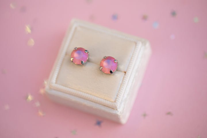 Pink opal stud earrings on a beige jewelry box with a pink background