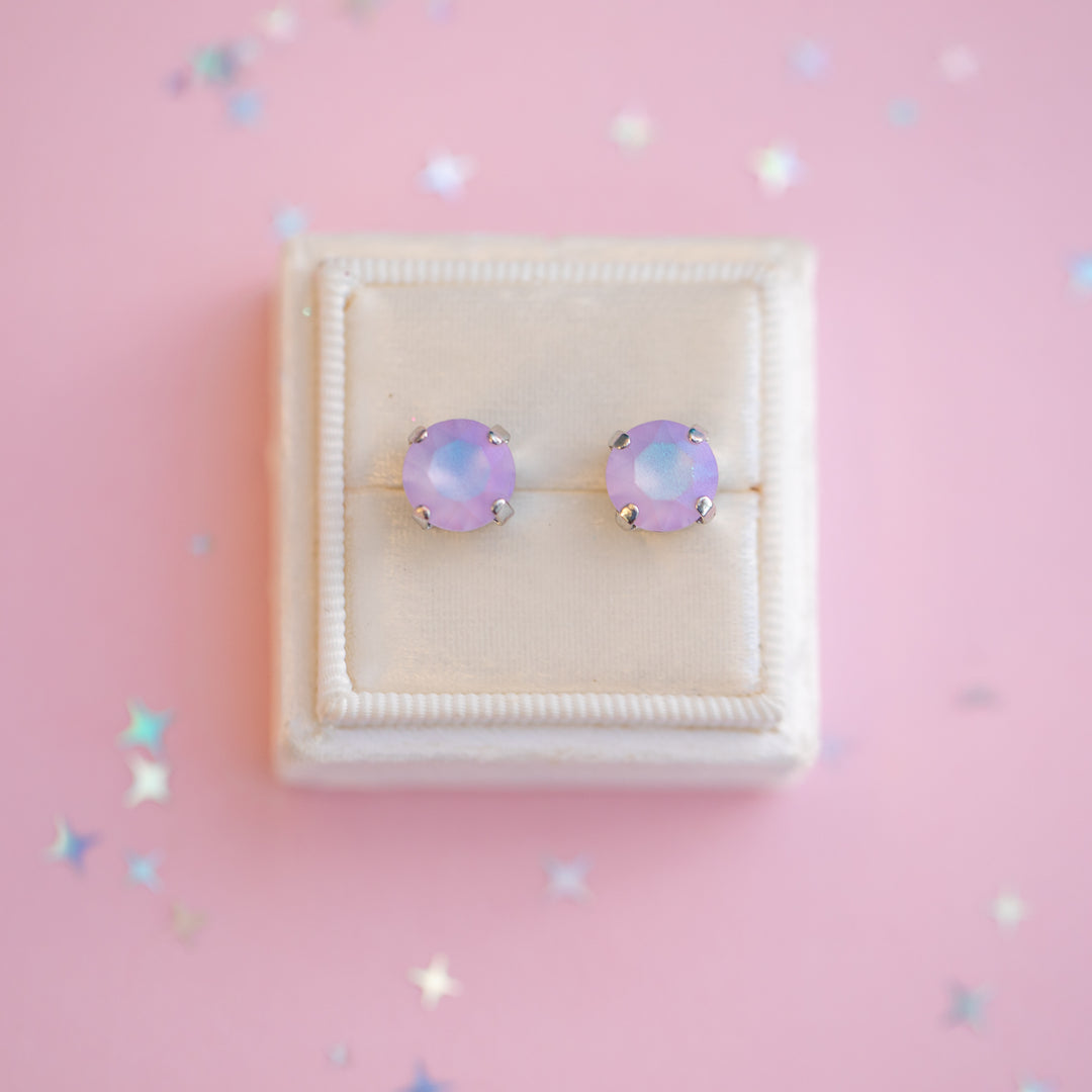 Pair of purple opal stud earrings on a pink background