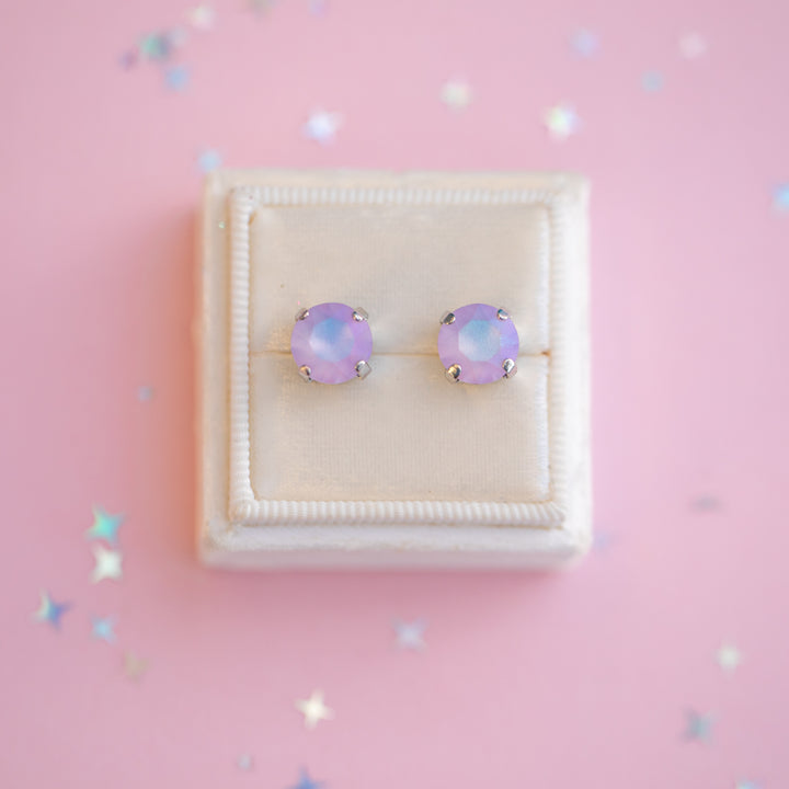 Pair of purple opal stud earrings on a pink background