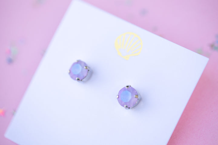 purple stud earrings on a white card with a logo against a pink background