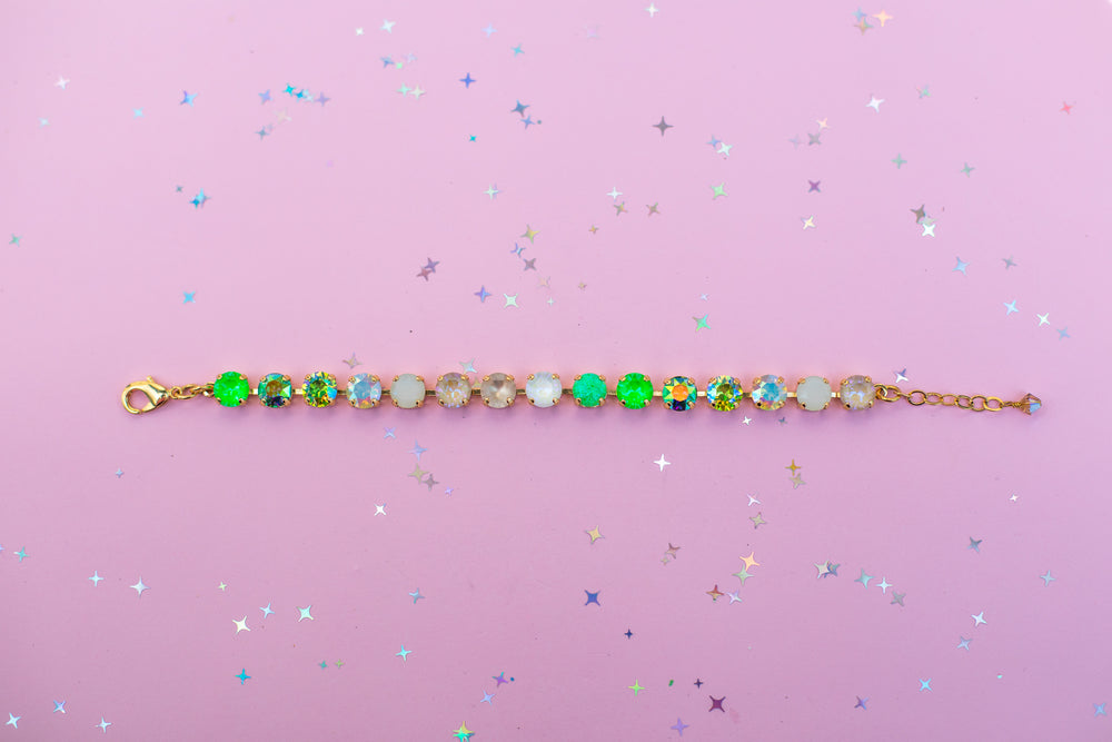 Gold bracelet with colorful beads on a pink background