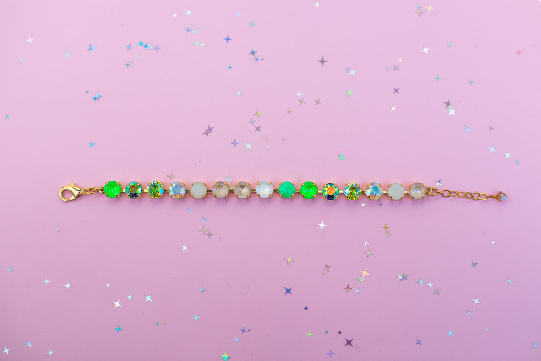 Gold bracelet with colorful beads on a pink background
