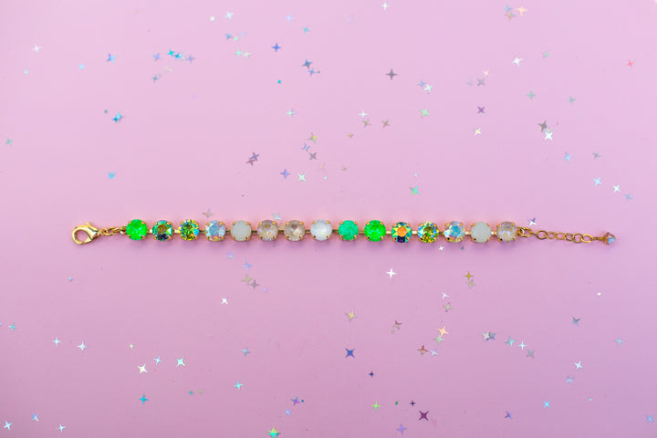 Gold bracelet with colorful beads on a pink background