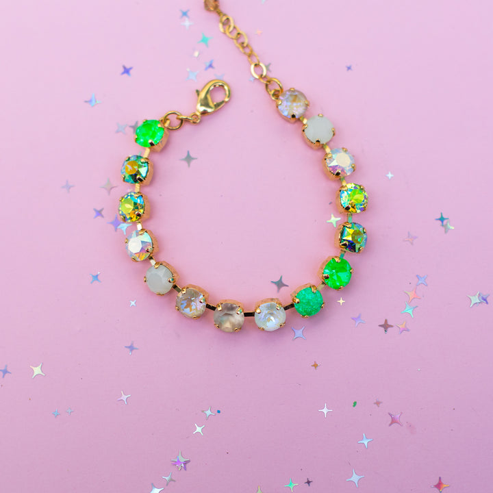 Bracelet with green and gold beads on a pink background