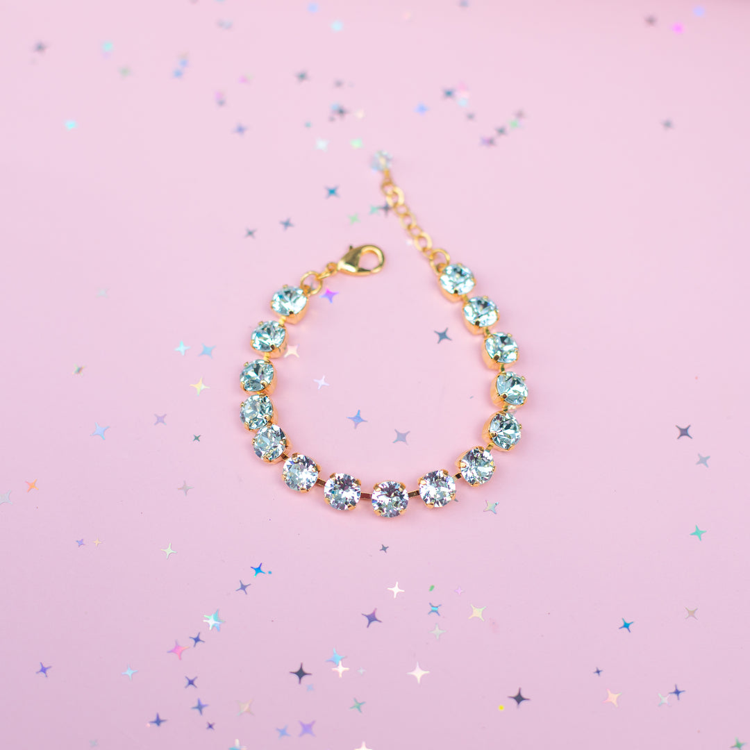 Gold bracelet with turquoise stones on a pink background with star confetti