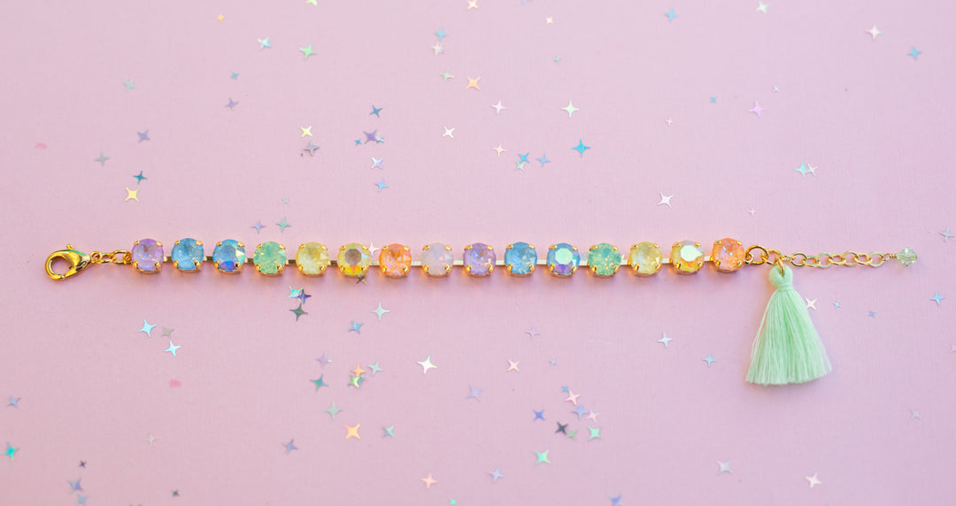 Bracelet with colorful beads and a green tassel on a pink background