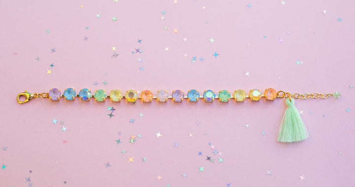 Bracelet with colorful beads and a green tassel on a pink background