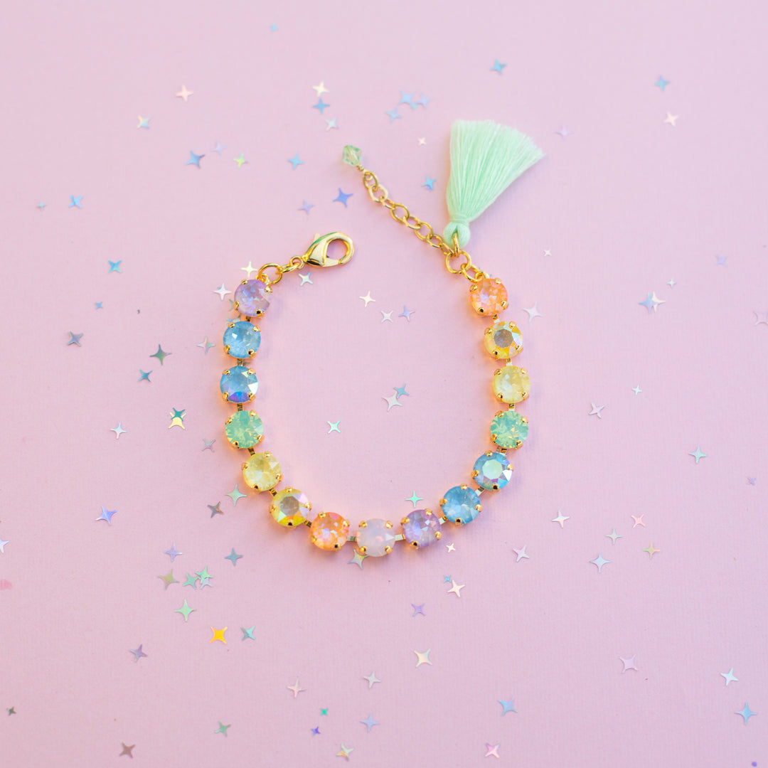 Colorful beaded bracelet with a tassel on a pink background