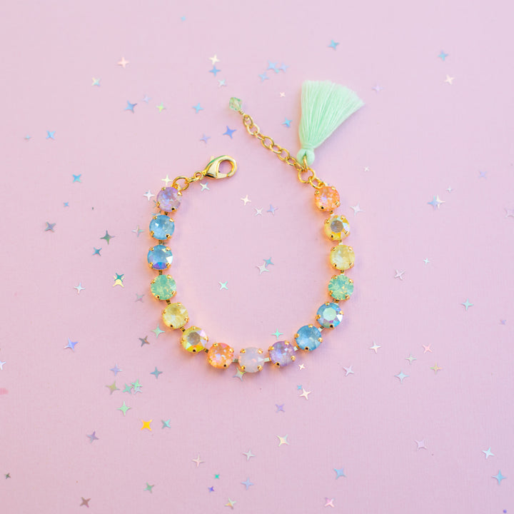 Colorful beaded bracelet with a tassel on a pink background